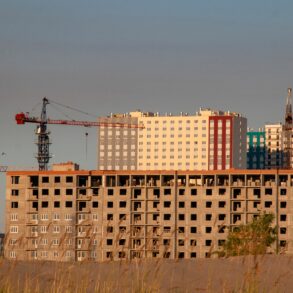 строительная площадка с недостроенным многоэтажным зданием и башенными кранами