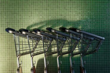 Несколько пустых металлических магазинных тележек у зеленой плиточной стены