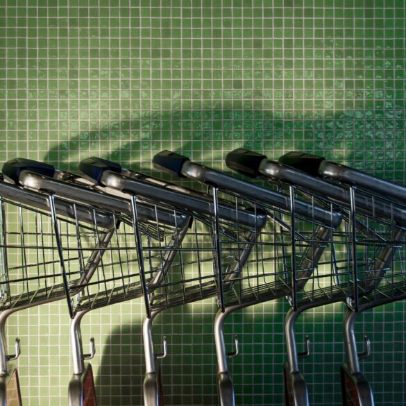 Несколько пустых металлических магазинных тележек у зеленой плиточной стены