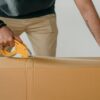 Мужчина заклеивает картонную коробку клейкой лентой
