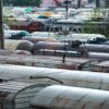 Ряд ржавых железнодорожных цистерн на стоянке за забором