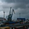 Порт с грузовым судном, портовыми кранами и контейнерами под пасмурным небом