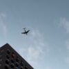 Пассажирский самолёт над углом многоэтажного жилого дома
