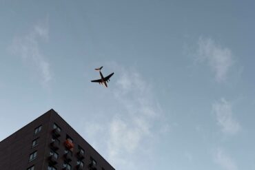 Пассажирский самолёт над углом многоэтажного жилого дома